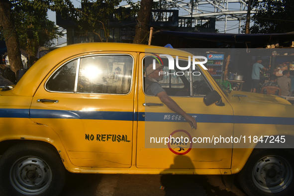 A yellow taxi driver sits inside his taxi and waits for passengers at a taxi stand in Kolkata, India, on December 8, 2024. Kolkata says good...