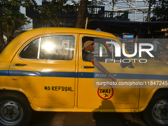 A yellow taxi driver sits inside his taxi and waits for passengers at a taxi stand in Kolkata, India, on December 8, 2024. Kolkata says good...