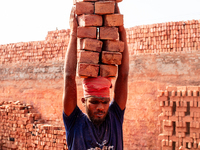 In Narsingdi, Dhaka, Bangladesh, on December 8, 2024, laborers carry piles of bricks weighing more than 15 kg on their heads in a brick kiln...