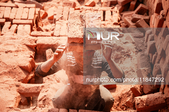 In Narsingdi, Dhaka, Bangladesh, on December 8, 2024, laborers carry piles of bricks weighing more than 15 kg on their heads in a brick kiln...