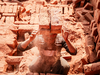 In Narsingdi, Dhaka, Bangladesh, on December 8, 2024, laborers carry piles of bricks weighing more than 15 kg on their heads in a brick kiln...