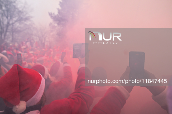 KRAKOW, POLAND - DECEMBER 08: Motorcycle riders dressed as Santa Claus take pictures with their mobile phones during a burnout demonstration...