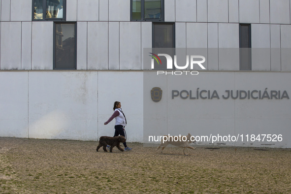 A person walks her dogs by the Judiciary Police Headquarters in Lisbon, Portugal, on December 8, 2024. The Judiciary Police (PJ) carry out a...