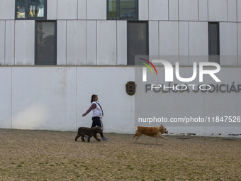 A person walks her dogs by the Judiciary Police Headquarters in Lisbon, Portugal, on December 8, 2024. The Judiciary Police (PJ) carry out a...