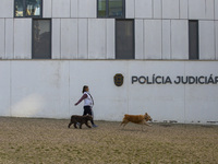 A person walks her dogs by the Judiciary Police Headquarters in Lisbon, Portugal, on December 8, 2024. The Judiciary Police (PJ) carry out a...