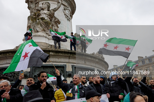 Members of the Syrian community and their supporters wave opposition flags as they gather in Paris on December 8, 2024, to celebrate the fal...