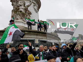 Members of the Syrian community and their supporters wave opposition flags as they gather in Paris on December 8, 2024, to celebrate the fal...