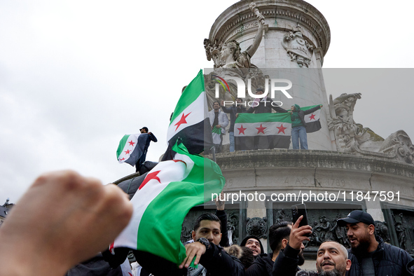 Members of the Syrian community and their supporters wave opposition flags as they gather in Paris on December 8, 2024, to celebrate the fal...