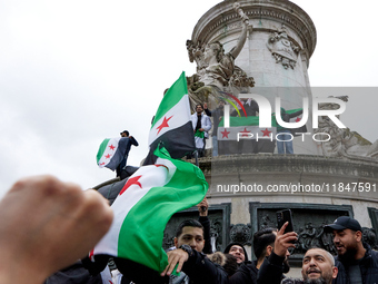 Members of the Syrian community and their supporters wave opposition flags as they gather in Paris on December 8, 2024, to celebrate the fal...