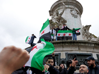 Members of the Syrian community and their supporters wave opposition flags as they gather in Paris on December 8, 2024, to celebrate the fal...