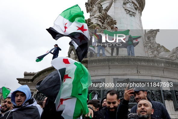 Members of the Syrian community and their supporters wave opposition flags as they gather in Paris on December 8, 2024, to celebrate the fal...