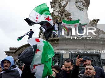 Members of the Syrian community and their supporters wave opposition flags as they gather in Paris on December 8, 2024, to celebrate the fal...