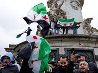 Members of the Syrian community and their supporters wave opposition flags as they gather in Paris on December 8, 2024, to celebrate the fal...