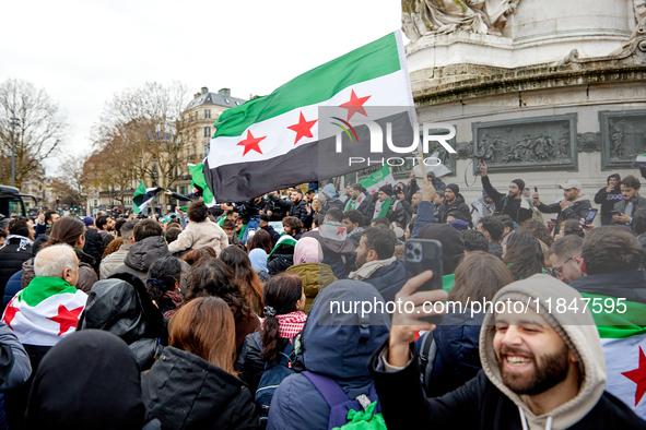 Members of the Syrian community and their supporters wave opposition flags as they gather in Paris on December 8, 2024, to celebrate the fal...