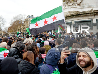 Members of the Syrian community and their supporters wave opposition flags as they gather in Paris on December 8, 2024, to celebrate the fal...