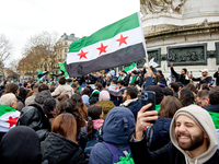 Members of the Syrian community and their supporters wave opposition flags as they gather in Paris on December 8, 2024, to celebrate the fal...