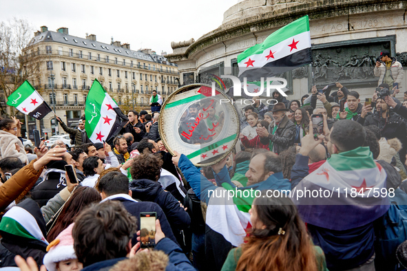 Members of the Syrian community and their supporters wave opposition flags as they gather in Paris on December 8, 2024, to celebrate the fal...