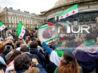 Members of the Syrian community and their supporters wave opposition flags as they gather in Paris on December 8, 2024, to celebrate the fal...