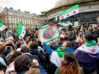 Members of the Syrian community and their supporters wave opposition flags as they gather in Paris on December 8, 2024, to celebrate the fal...