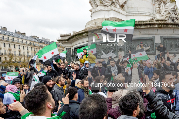 Members of the Syrian community and their supporters wave opposition flags as they gather in Paris on December 8, 2024, to celebrate the fal...