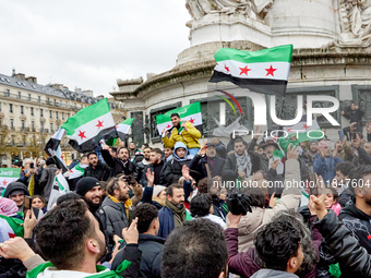 Members of the Syrian community and their supporters wave opposition flags as they gather in Paris on December 8, 2024, to celebrate the fal...