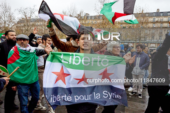 Members of the Syrian community and their supporters wave opposition flags as they gather in Paris on December 8, 2024, to celebrate the fal...