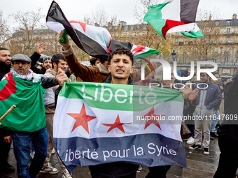 Members of the Syrian community and their supporters wave opposition flags as they gather in Paris on December 8, 2024, to celebrate the fal...