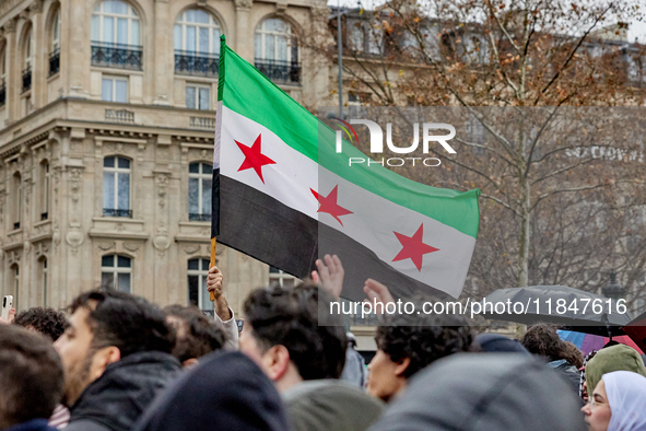 Members of the Syrian community and their supporters wave opposition flags as they gather in Paris on December 8, 2024, to celebrate the fal...