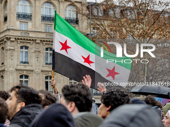 Members of the Syrian community and their supporters wave opposition flags as they gather in Paris on December 8, 2024, to celebrate the fal...