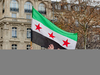 Members of the Syrian community and their supporters wave opposition flags as they gather in Paris on December 8, 2024, to celebrate the fal...