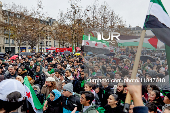 Members of the Syrian community and their supporters wave opposition flags as they gather in Paris on December 8, 2024, to celebrate the fal...