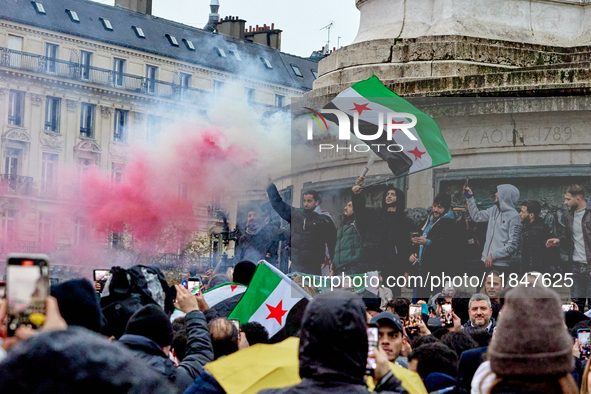 Members of the Syrian community and their supporters wave opposition flags as they gather in Paris on December 8, 2024, to celebrate the fal...