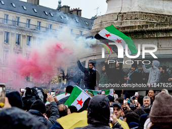 Members of the Syrian community and their supporters wave opposition flags as they gather in Paris on December 8, 2024, to celebrate the fal...