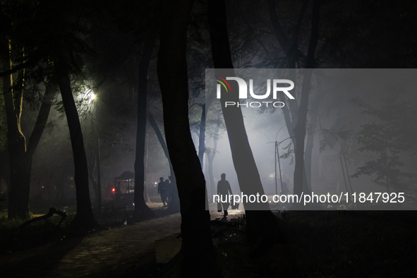 People walk through a park covered in light fog as winter begins in Dhaka, Bangladesh, on December 8, 2024. 