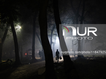 People walk through a park covered in light fog as winter begins in Dhaka, Bangladesh, on December 8, 2024. (