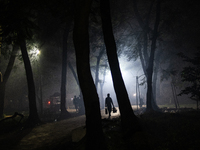 People walk through a park covered in light fog as winter begins in Dhaka, Bangladesh, on December 8, 2024. (