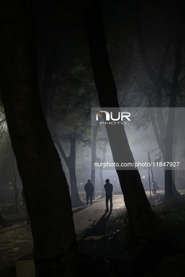 People walk through a park covered in light fog as winter begins in Dhaka, Bangladesh, on December 8, 2024. 