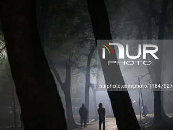 People walk through a park covered in light fog as winter begins in Dhaka, Bangladesh, on December 8, 2024. (