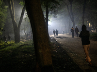 People walk through a park covered in light fog as winter begins in Dhaka, Bangladesh, on December 8, 2024. (