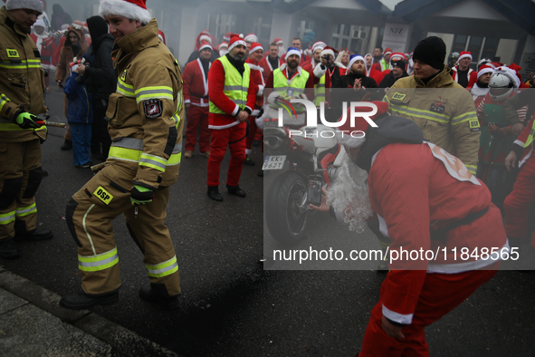 Motorcyclists in Santa costumes burn a tire on their motorcycle while handing out gifts at the University Children's Hospital in Krakow, Pol...