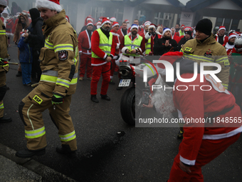 Motorcyclists in Santa costumes burn a tire on their motorcycle while handing out gifts at the University Children's Hospital in Krakow, Pol...