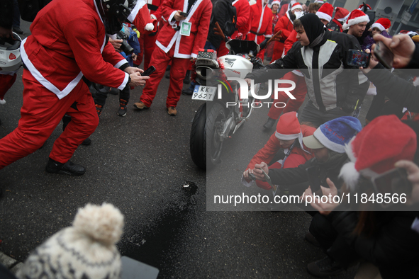 Motorcyclists in Santa costumes burn a tire on their motorcycle while handing out gifts at the University Children's Hospital in Krakow, Pol...