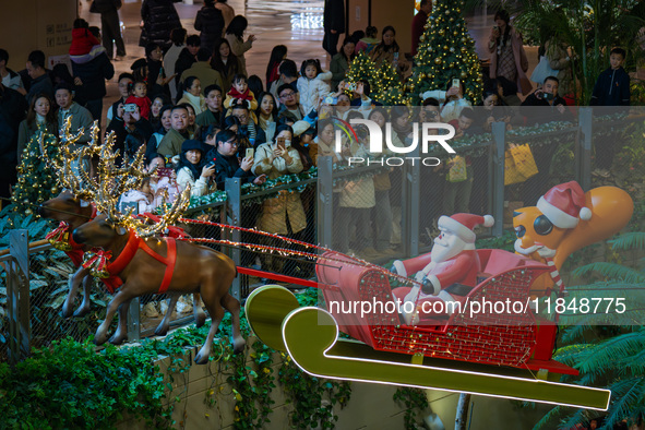 Visitors watch Santa Claus' flying sleigh ride at Halo Shopping Park in Chongqing, China, on December 8, 2024. 