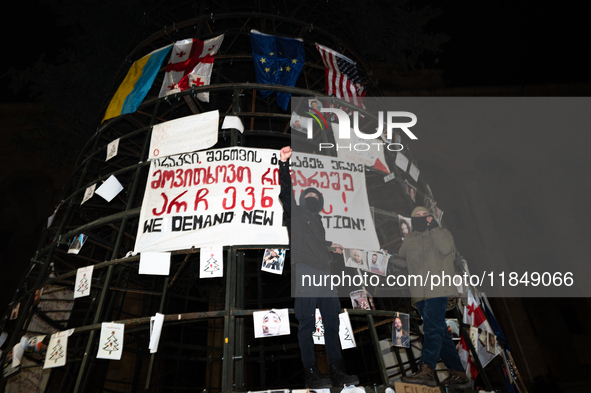 A partially installed artificial Christmas tree with pictures of individuals reportedly beaten by police, which demonstrators attach to the...