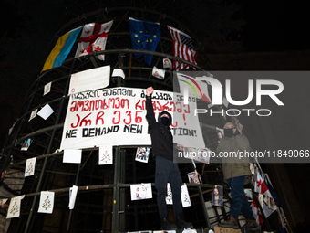 A partially installed artificial Christmas tree with pictures of individuals reportedly beaten by police, which demonstrators attach to the...