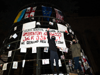 A partially installed artificial Christmas tree with pictures of individuals reportedly beaten by police, which demonstrators attach to the...