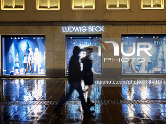 On a rainy evening in Munich, Bavaria, Germany, on December 8, 2024, during the Christmas season, the streets come alive with the glow of fe...