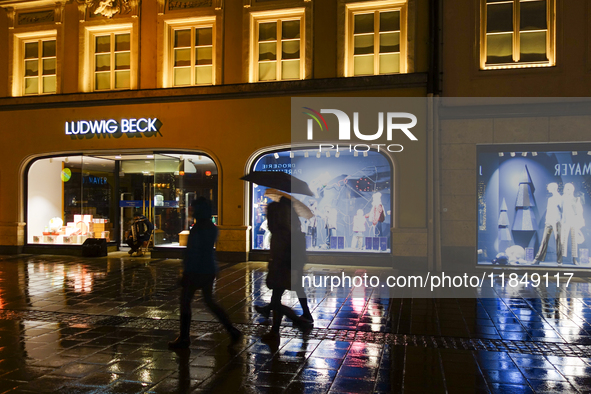 On a rainy evening in Munich, Bavaria, Germany, on December 8, 2024, during the Christmas season, the streets come alive with the glow of fe...