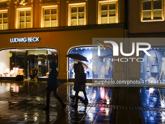 On a rainy evening in Munich, Bavaria, Germany, on December 8, 2024, during the Christmas season, the streets come alive with the glow of fe...