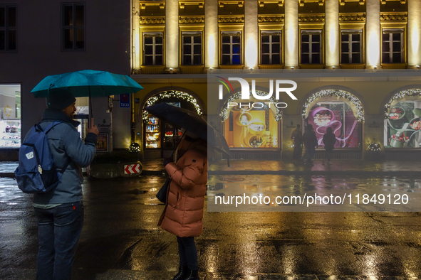 On a rainy evening in Munich, Bavaria, Germany, on December 8, 2024, during the Christmas season, the streets come alive with the glow of fe...